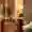 Einblick ins ein Komfortzimmer im Hotel Ritter Durbach. Eine Person öffnet die Tür und man kann ein fast bodentiefes Fenster mit grünen Vorhängen sehen mit einem kleinen Tisch davor auf dem eine Wasserflasche steht. Ein großer Ohrensessel und ein Schreibtisch mit einem pinken Polsterstuhl und eine angeschaltete Stehlampe sind ebenfalls zu sehen.